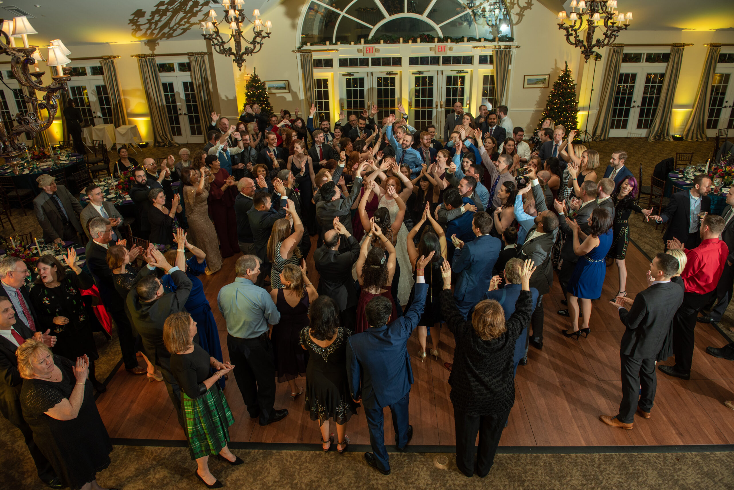 Bride surrounded by guests with hands raised on a packed dance floor at The Riverhouse at Goodspeed Station in Haddam CT