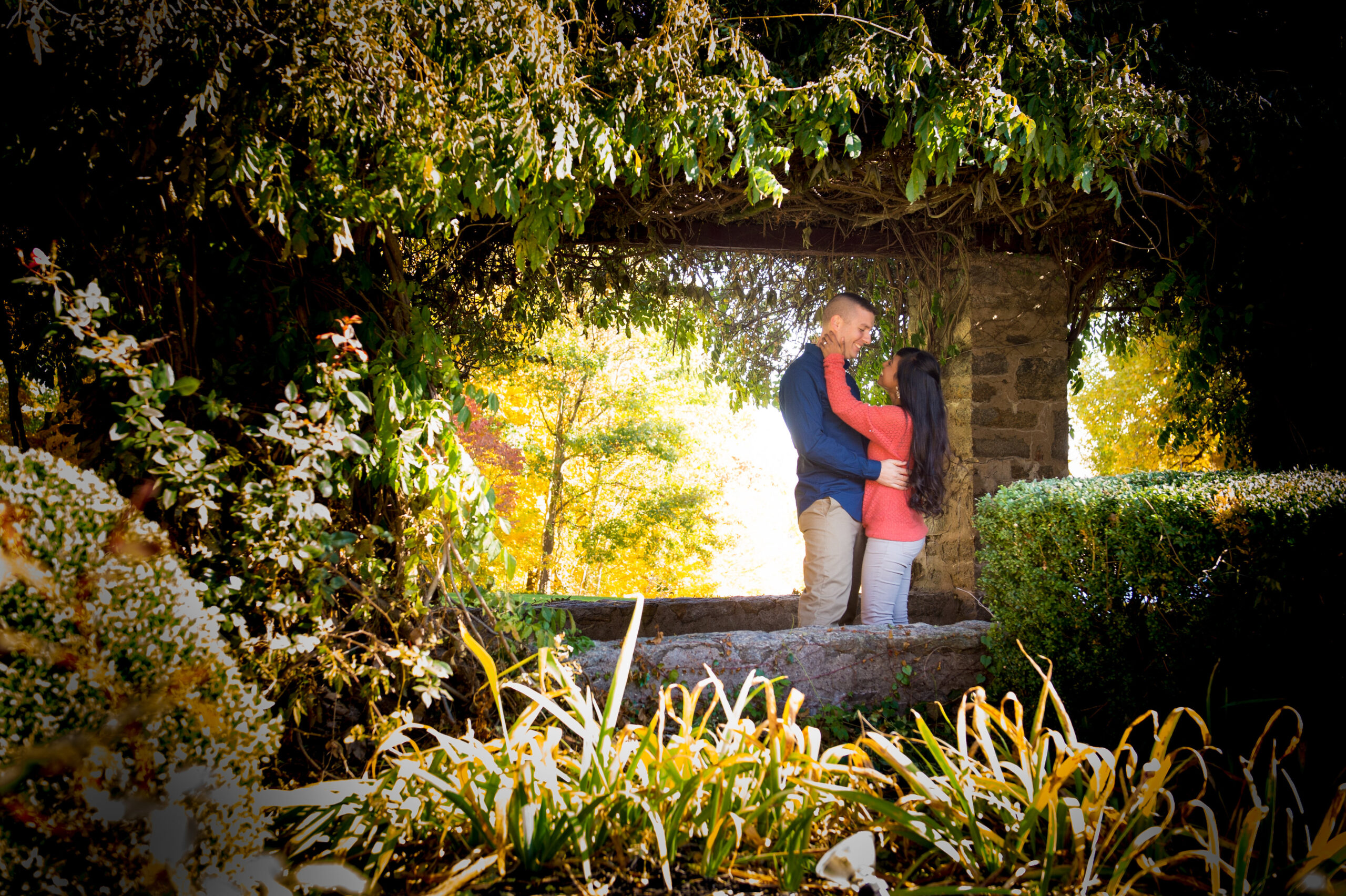 Engaged couple in a garden archway during an engagement session at St. Clements Castle in Portland CT