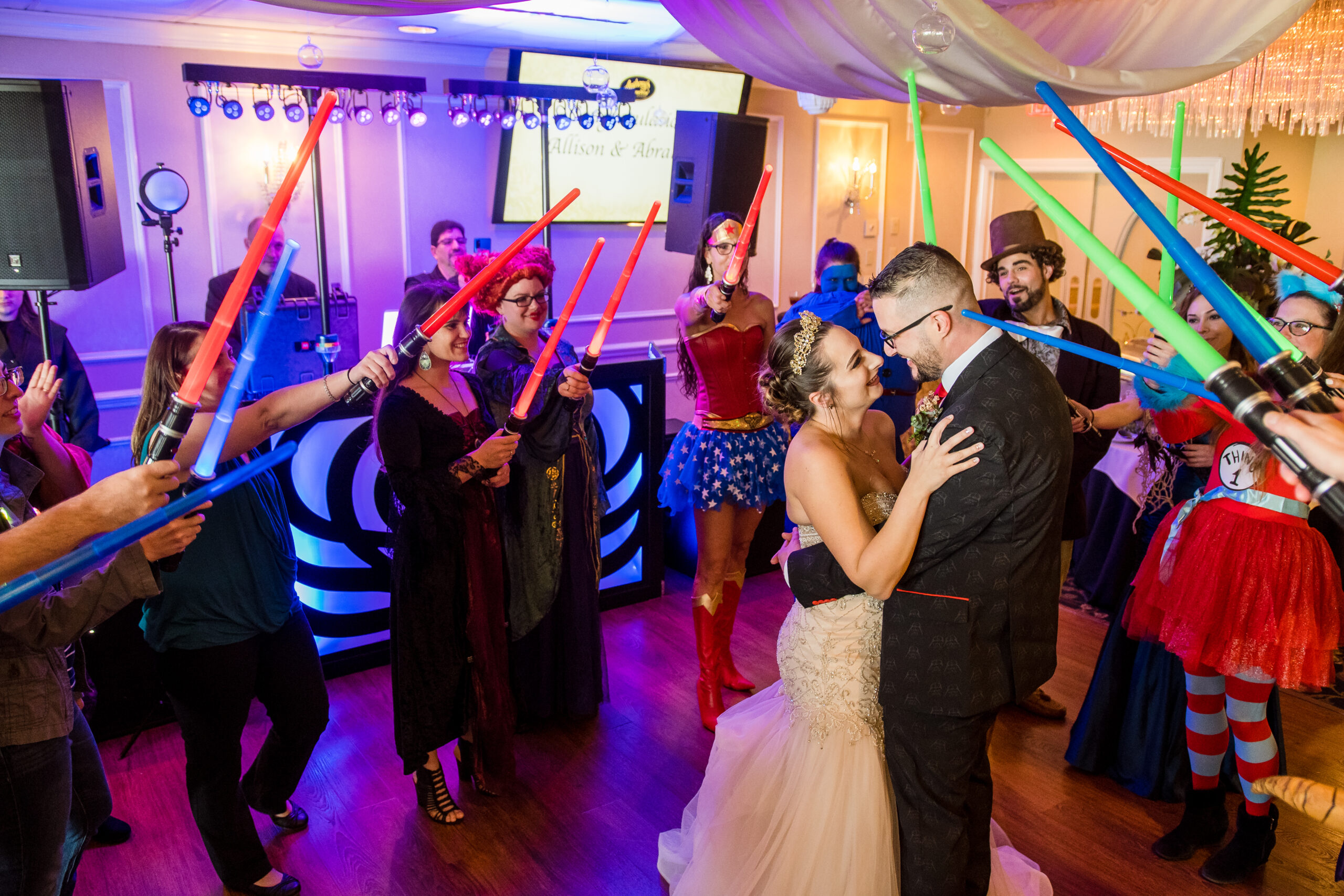 Bride and groom sharing a first dance surrounded by costumed guests raising toy lightsabers at a themed wedding at Anthony's Oceanview in New Haven CT