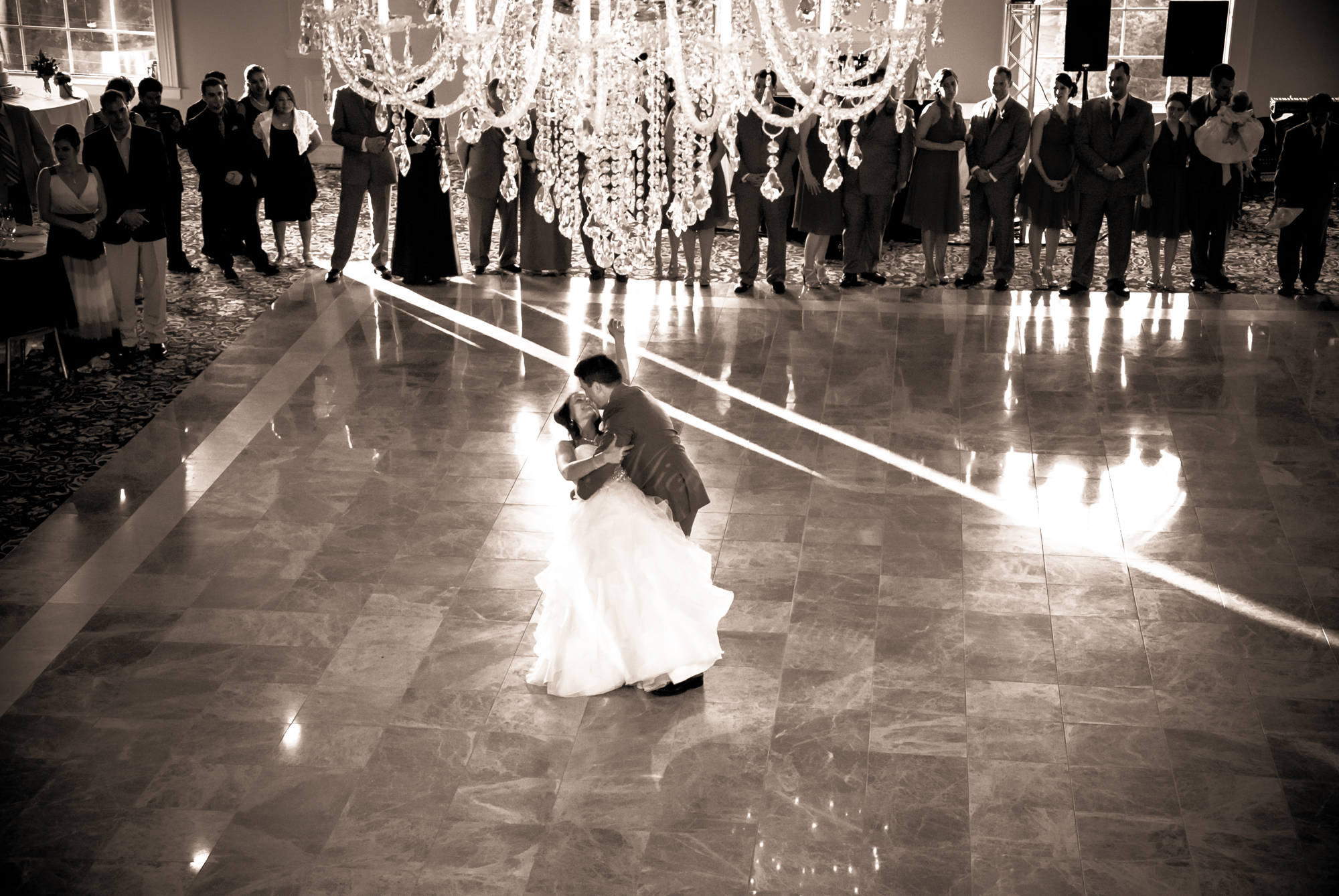 Bride and groom sharing their first dance dip under a crystal chandelier at Aria in Prospect CT