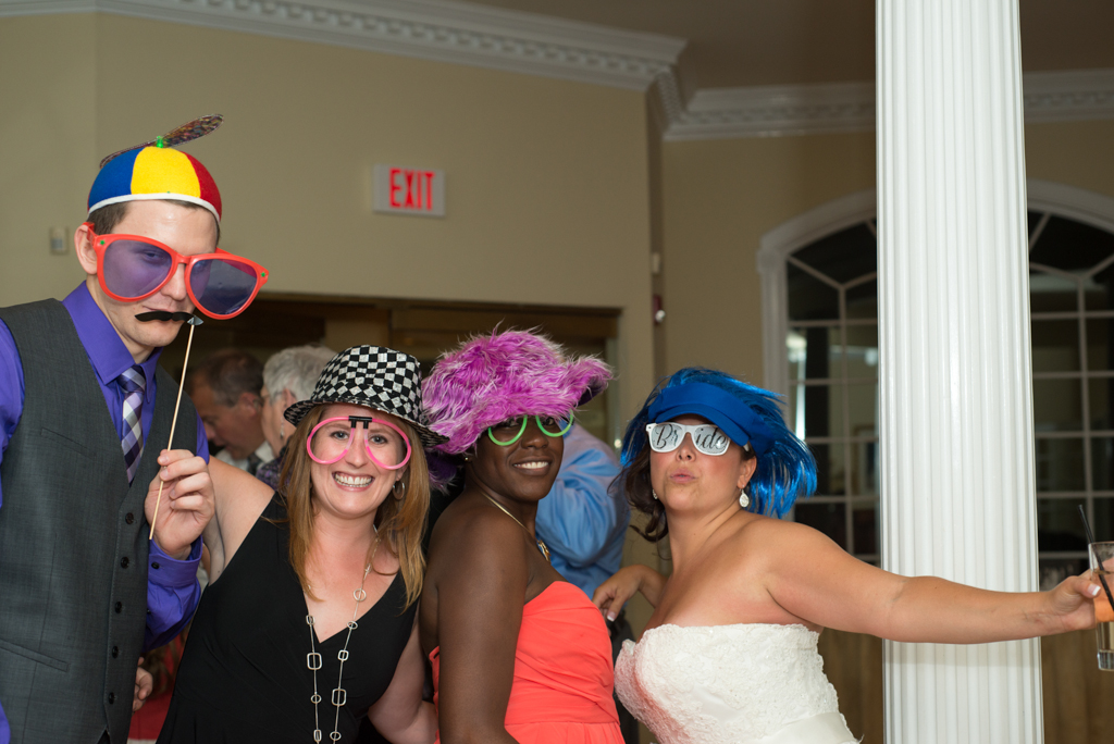 Bride and friends laughing with props in a photo booth at the Candlewood Inn in Brookfield CT
