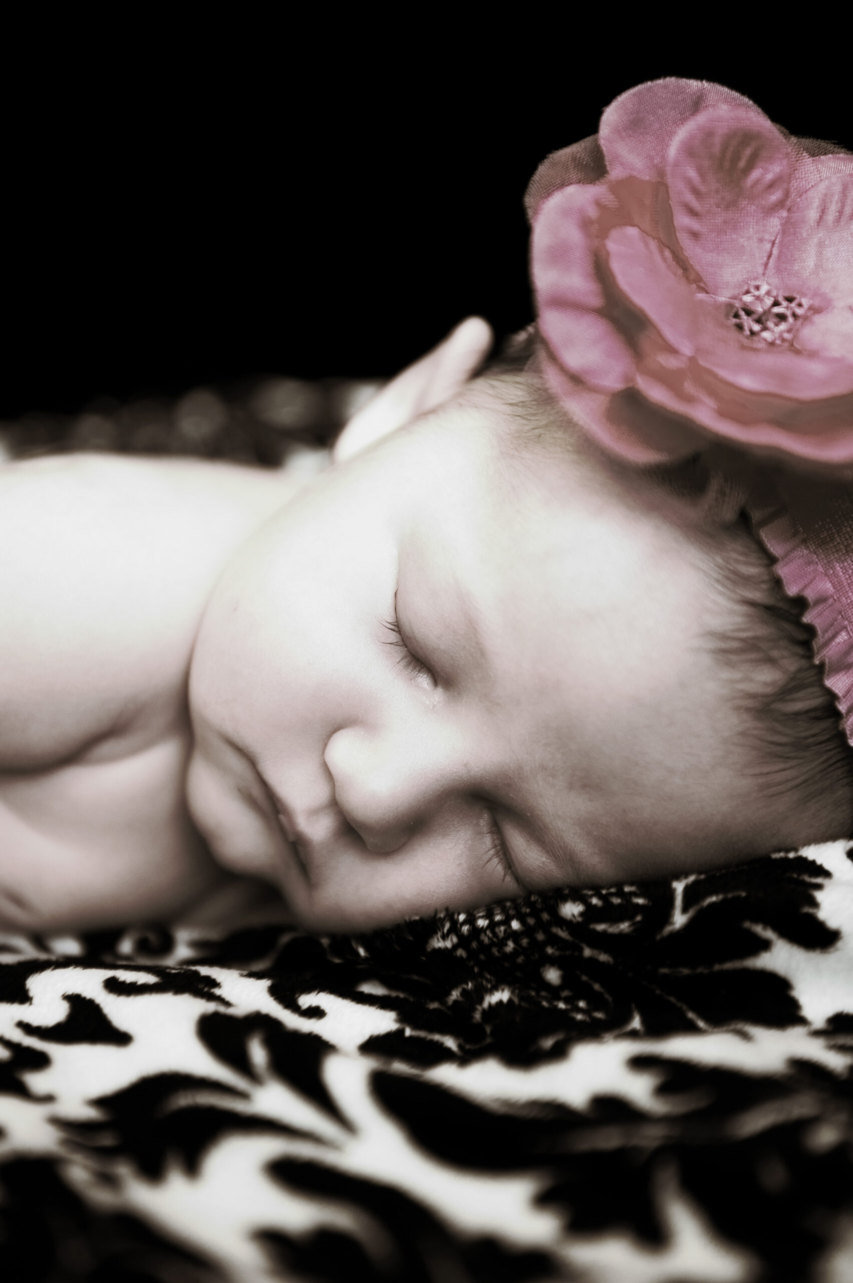 Sleeping newborn in floral bonnet during a Connecticut newborn portrait session