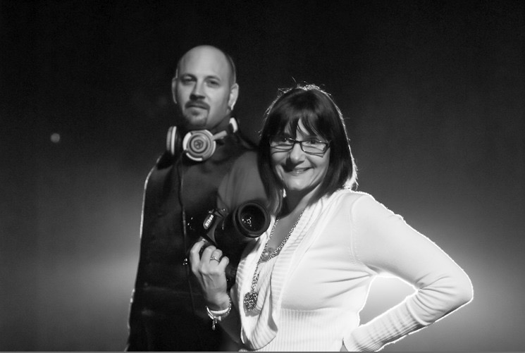 Dave and Connie Krevalin of Lyrical Lens Events, DJ with headphones and photographer with camera in black and white portrait