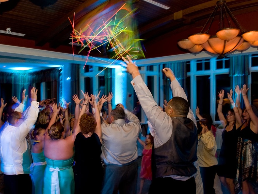 Wedding guests with hands up and glow sticks on the dance floor with blue uplighting at Lake of Isles in North Stonington CT