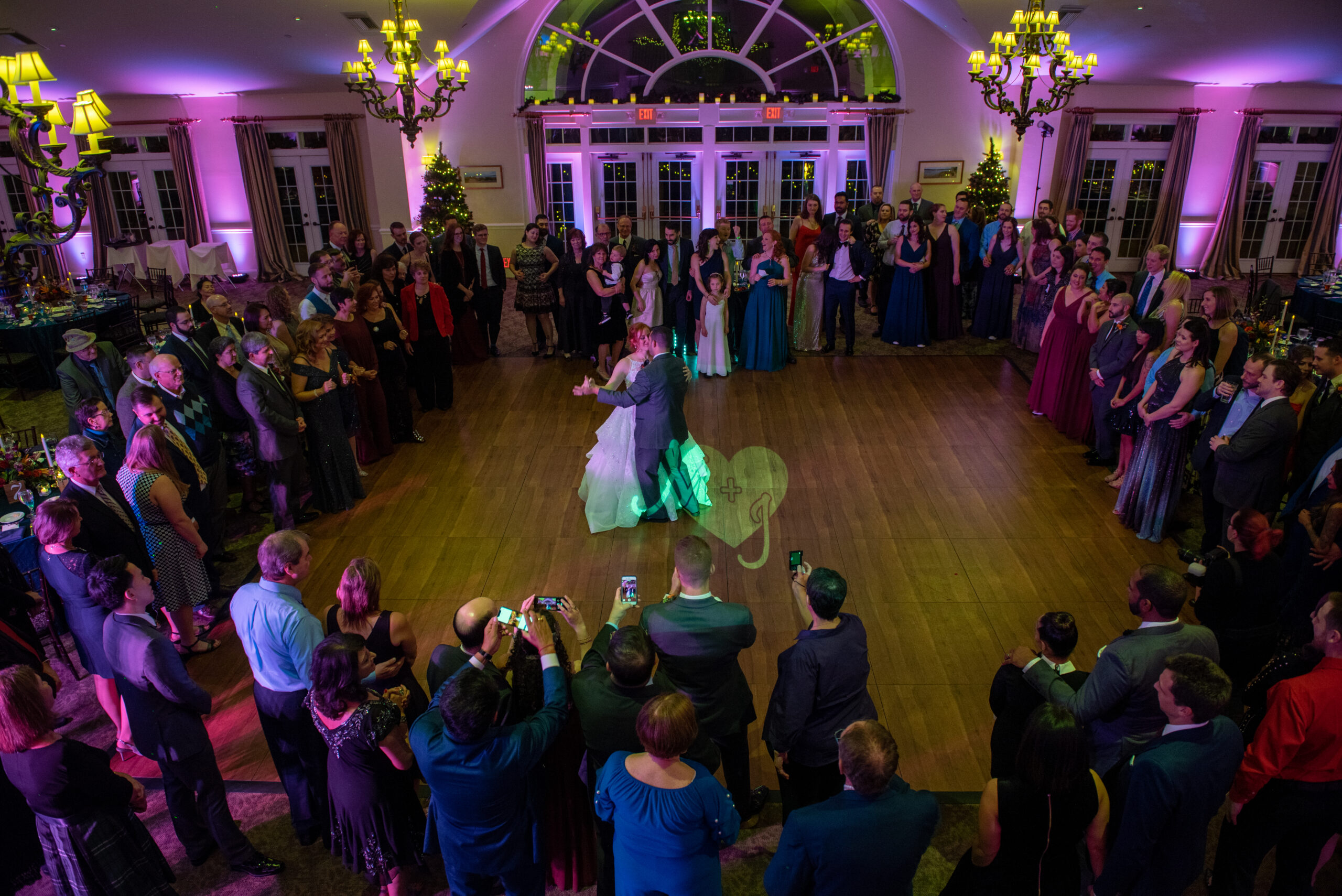 Bride and groom first dance surrounded by guests under pink and purple uplighting at The Riverhouse at Goodspeed Station in Haddam CT