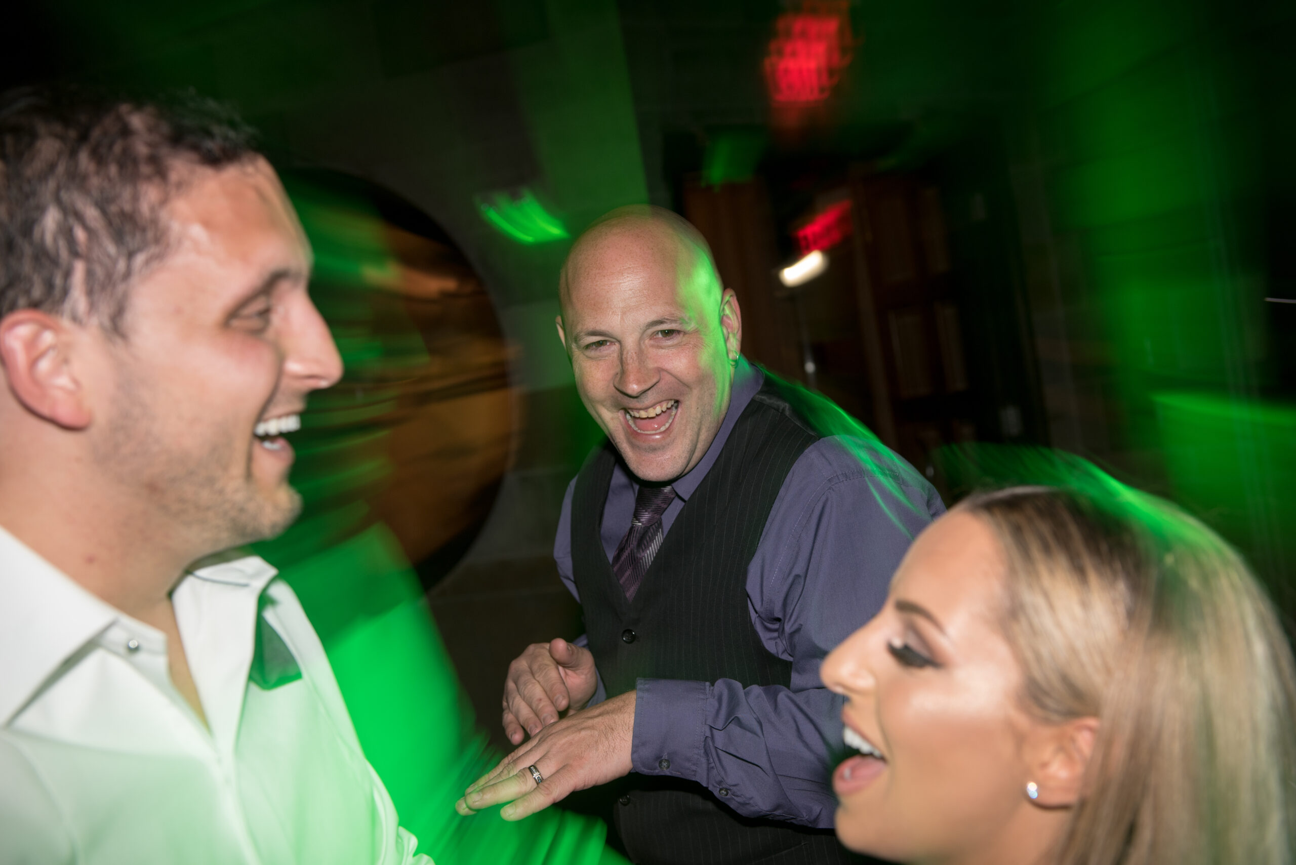 Wedding DJ laughing with the bride and groom on the dance floor under green party lighting at the Society Room of Hartford in Hartford CT