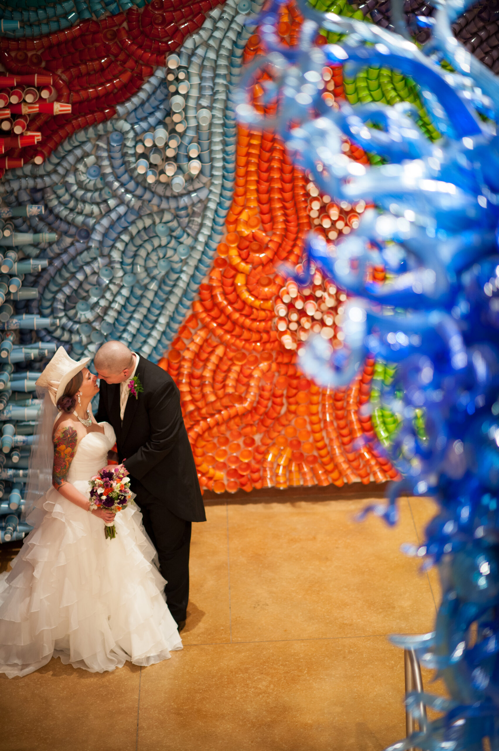 Bride and groom kissing in front of a colorful mosaic art installation at the New Britain Museum of American Art in New Britain CT